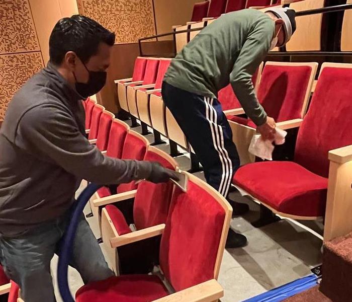 SERVPRO employees cleaning the seats of an auditorium.