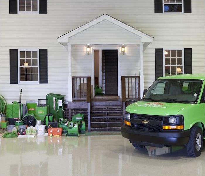 a green SERVPRO truck and restoration tools inside a showroom
