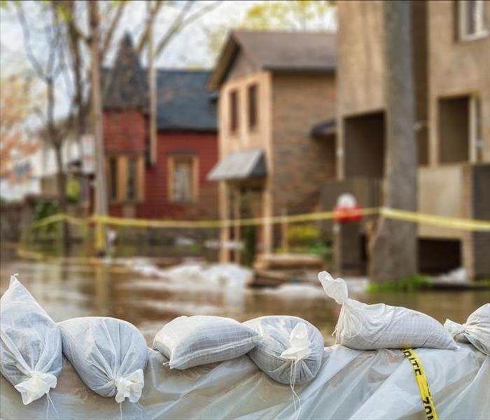 Sandbags can be seen in the foreground of a neighborhood of homes that have experienced a flood.