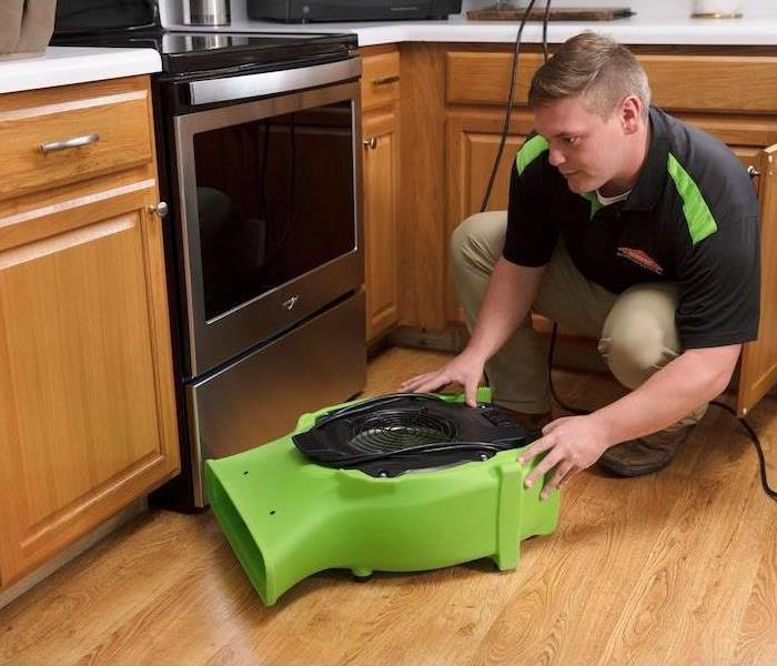 SERVPRO technician placing air mover in kitchen